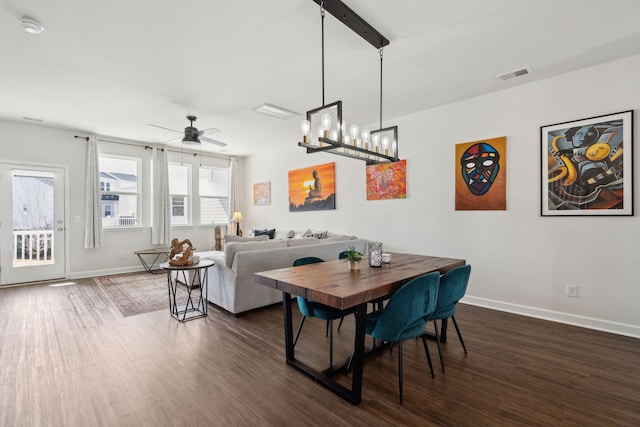 dining space featuring dark hardwood / wood-style flooring and ceiling fan with notable chandelier