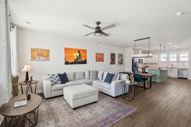 living room with sink, ceiling fan with notable chandelier, and dark hardwood / wood-style flooring