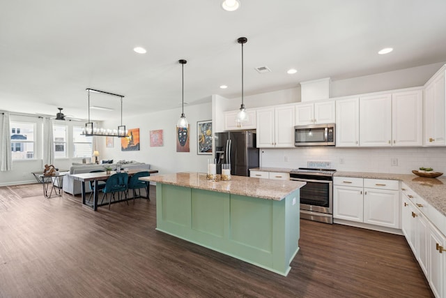 kitchen with a center island, appliances with stainless steel finishes, light stone countertops, decorative backsplash, and white cabinets