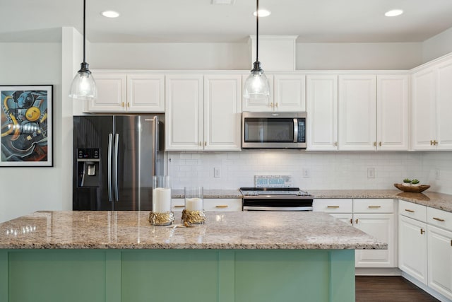 kitchen featuring light stone countertops, appliances with stainless steel finishes, pendant lighting, and white cabinets