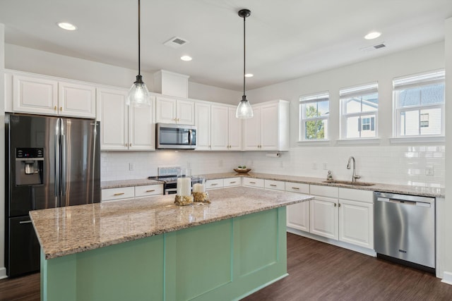 kitchen with stainless steel appliances, sink, a kitchen island, and white cabinets