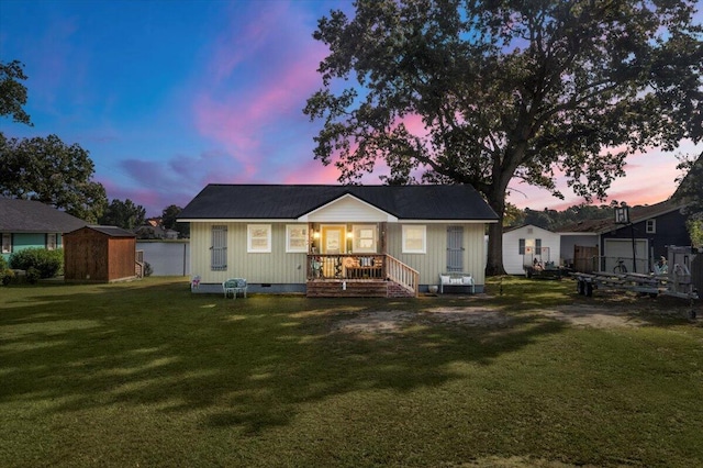 back house at dusk with a yard and a porch