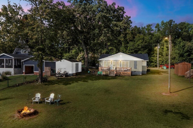 yard at dusk featuring a fire pit and a shed