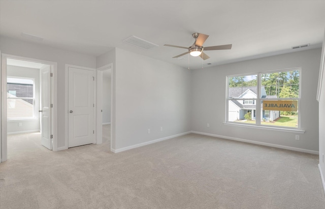 empty room with visible vents, light carpet, and baseboards