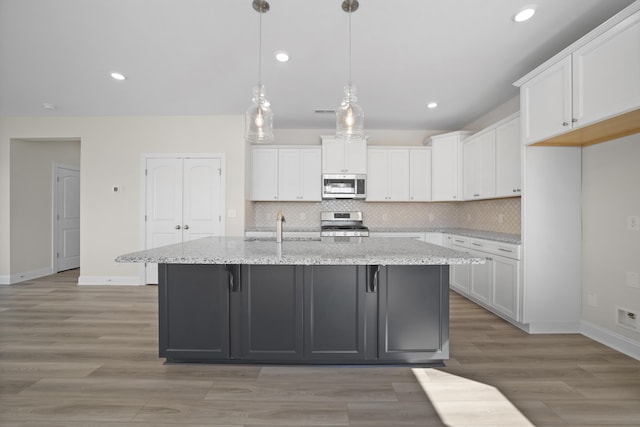 kitchen featuring appliances with stainless steel finishes, white cabinetry, light wood-style flooring, and decorative backsplash