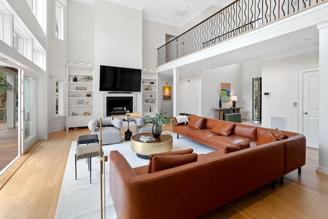 living area featuring crown molding, visible vents, and light wood-style floors