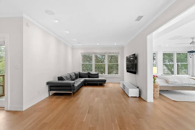 living room with light wood-style floors, visible vents, ornamental molding, and baseboards