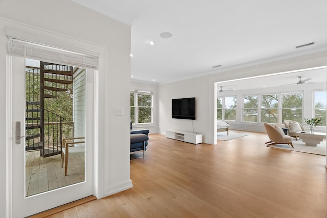 interior space featuring visible vents, ornamental molding, ceiling fan, light wood-type flooring, and baseboards