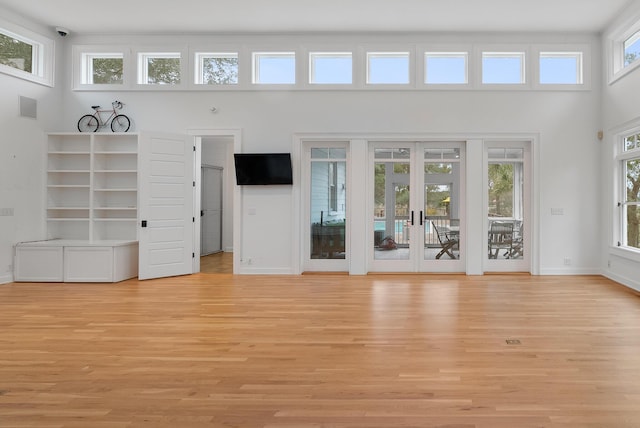 unfurnished living room featuring light wood-style floors, french doors, visible vents, and baseboards