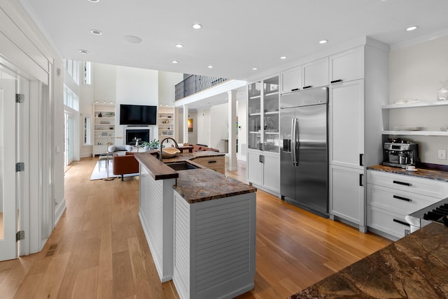 kitchen with stainless steel built in refrigerator, a fireplace, a sink, and light wood finished floors