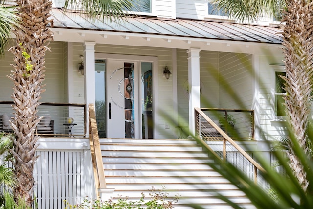 entrance to property with a standing seam roof, covered porch, and metal roof