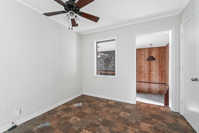 empty room with ceiling fan, crown molding, and wood walls