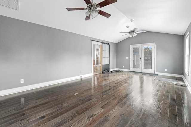 unfurnished living room featuring french doors, vaulted ceiling, dark hardwood / wood-style floors, a barn door, and ceiling fan