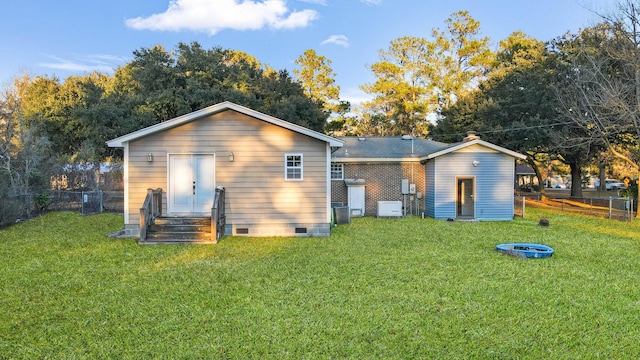 rear view of property featuring central air condition unit and a yard