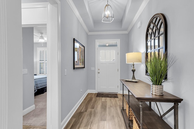 entrance foyer featuring crown molding, a tray ceiling, wood-type flooring, and a healthy amount of sunlight