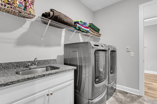 clothes washing area featuring cabinets, washer and clothes dryer, and sink