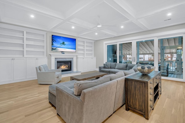 living room featuring built in shelves, light hardwood / wood-style floors, and beamed ceiling