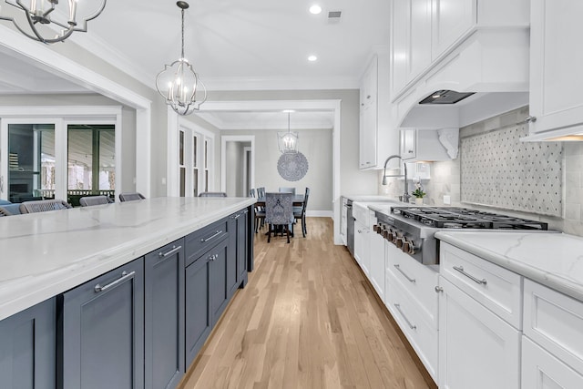 kitchen with stainless steel gas cooktop, light stone countertops, decorative backsplash, white cabinetry, and decorative light fixtures