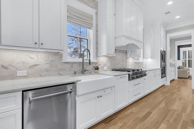 kitchen with sink, white cabinetry, backsplash, light stone countertops, and appliances with stainless steel finishes