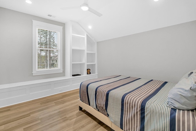 bedroom with ceiling fan, vaulted ceiling, and light wood-type flooring