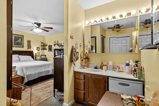 bathroom with a textured ceiling, ceiling fan, ensuite bath, and vanity