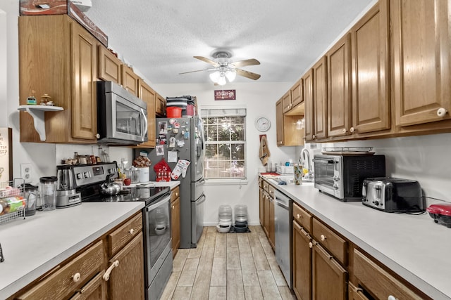 kitchen with a sink, light countertops, ceiling fan, and stainless steel appliances