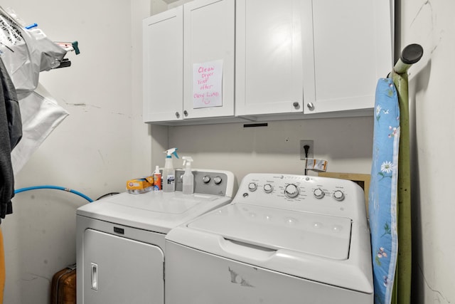 clothes washing area with separate washer and dryer and cabinet space