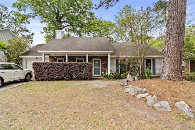 view of front of property with roof with shingles, a chimney, an attached garage, a front yard, and brick siding
