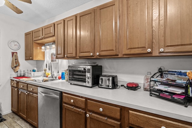 kitchen with dishwasher, a sink, light countertops, a ceiling fan, and brown cabinets