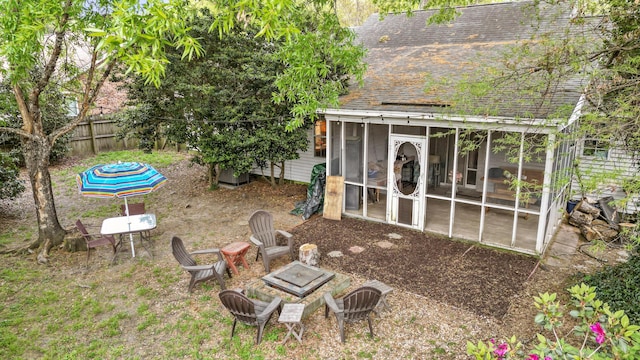 view of yard with fence, a fire pit, and a sunroom
