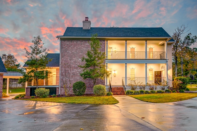 view of front of house featuring a porch, a balcony, and a yard