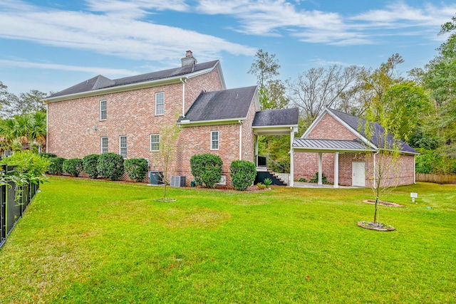 rear view of house featuring a lawn and central AC