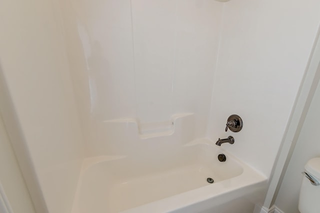 bathroom featuring tub / shower combination and toilet