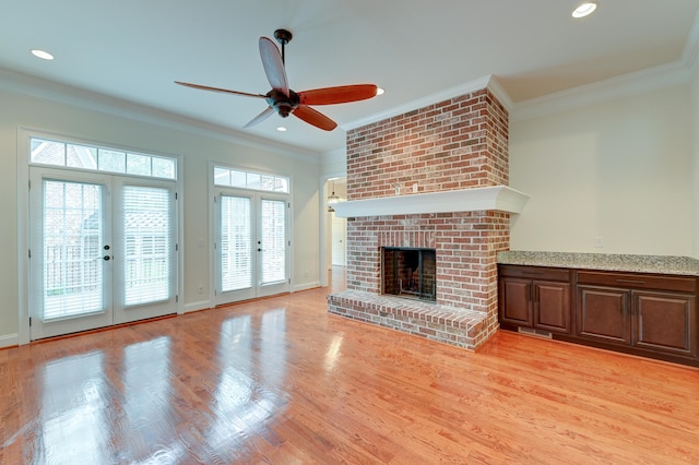 unfurnished living room with ornamental molding, french doors, a healthy amount of sunlight, and light hardwood / wood-style flooring