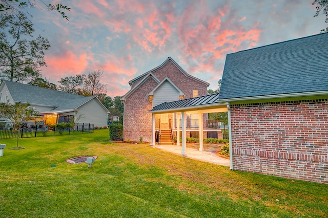 back house at dusk featuring a patio and a yard