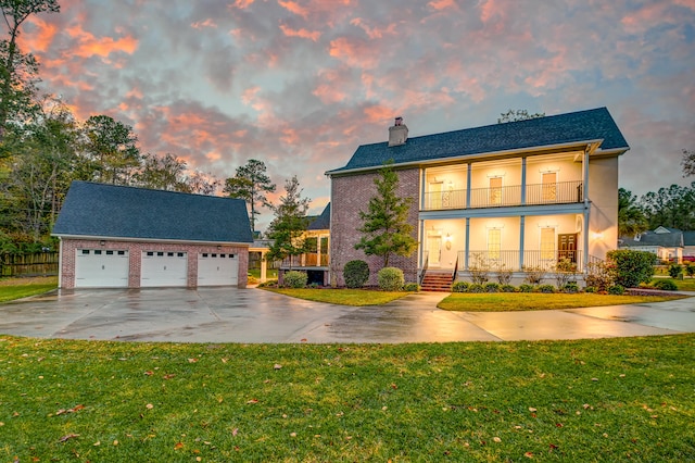 view of front of house with covered porch, a garage, a lawn, and a balcony