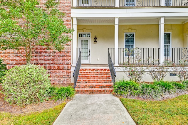 view of exterior entry featuring a porch and a balcony