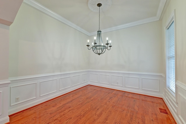 empty room with hardwood / wood-style flooring, a chandelier, and ornamental molding