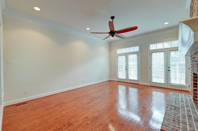 unfurnished room featuring a brick fireplace, a healthy amount of sunlight, french doors, and ornamental molding