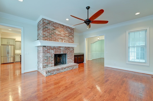 unfurnished living room with a fireplace, ceiling fan, light wood-type flooring, and crown molding