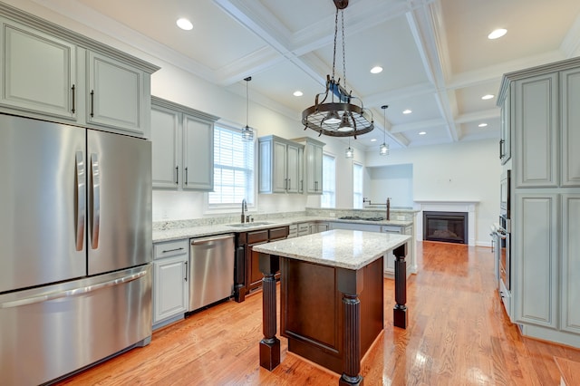 kitchen featuring light stone counters, light wood-type flooring, appliances with stainless steel finishes, a breakfast bar area, and a center island