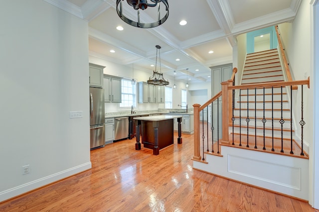 kitchen with stainless steel appliances, coffered ceiling, a kitchen island, light hardwood / wood-style flooring, and decorative light fixtures