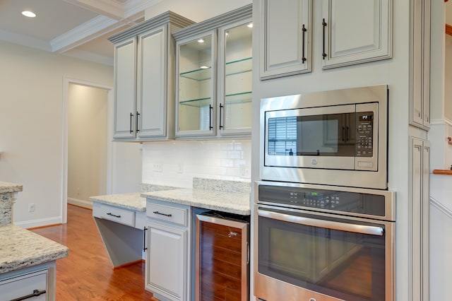 kitchen featuring stainless steel appliances, ornamental molding, light stone countertops, light hardwood / wood-style flooring, and wine cooler