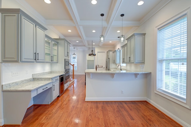 kitchen with light stone counters, kitchen peninsula, hanging light fixtures, beamed ceiling, and light wood-type flooring