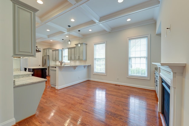 kitchen with light stone counters, a kitchen bar, coffered ceiling, kitchen peninsula, and light hardwood / wood-style flooring