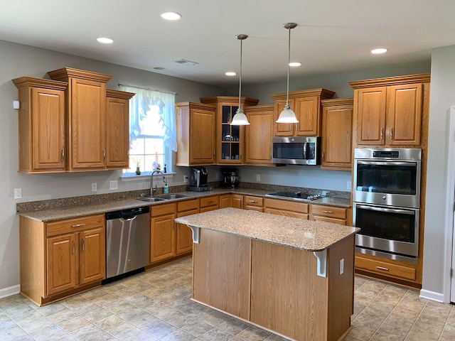 kitchen with hanging light fixtures, a center island, stone counters, stainless steel appliances, and sink