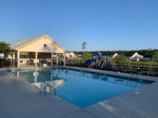 view of pool with a playground and a patio