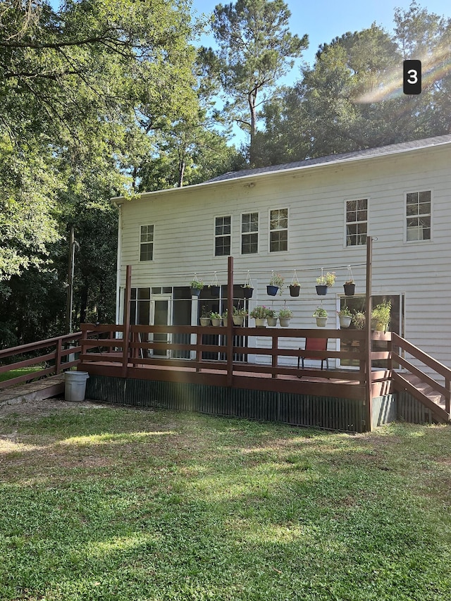 rear view of house featuring a lawn and a deck