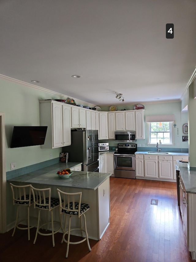 kitchen featuring light hardwood / wood-style floors, sink, white cabinets, kitchen peninsula, and appliances with stainless steel finishes