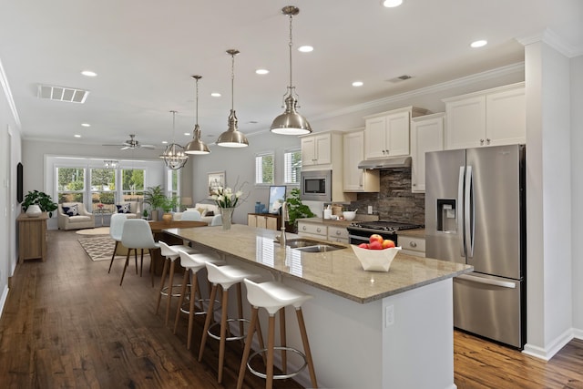 kitchen with visible vents, stainless steel appliances, under cabinet range hood, a sink, and backsplash